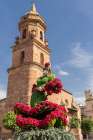 Andujar, Jaen Province, Andalusia, Spain. Red flowers and the bell tower of the San Miguel Church. Art Print